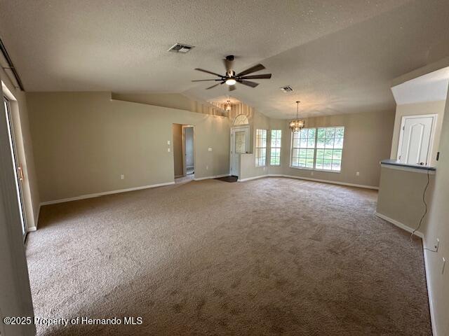 spare room with visible vents, carpet floors, lofted ceiling, a textured ceiling, and ceiling fan with notable chandelier