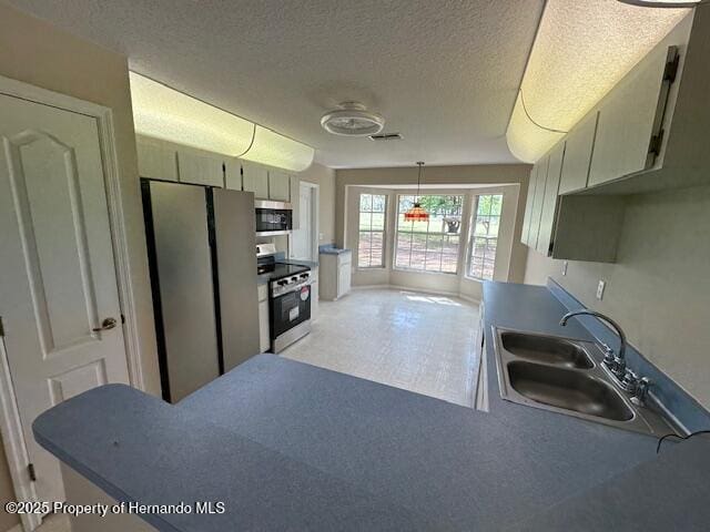 kitchen featuring visible vents, a sink, decorative light fixtures, a textured ceiling, and stainless steel appliances