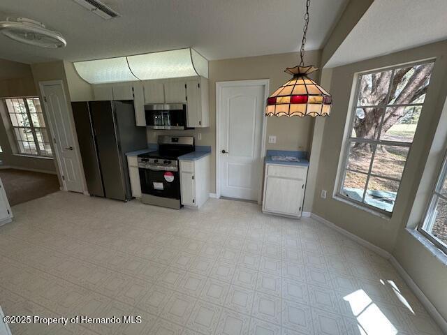 kitchen featuring a healthy amount of sunlight, pendant lighting, stainless steel appliances, and baseboards