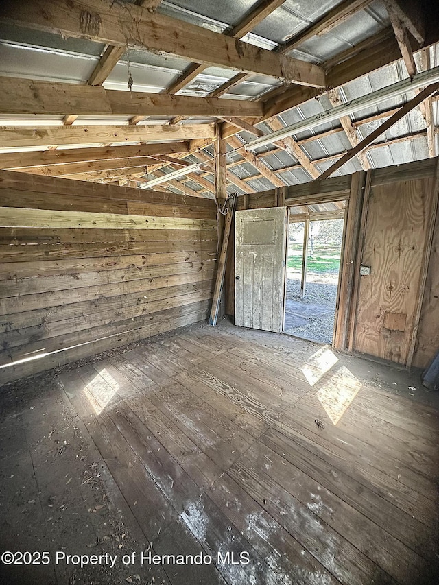 interior space featuring hardwood / wood-style flooring, wood walls, and vaulted ceiling