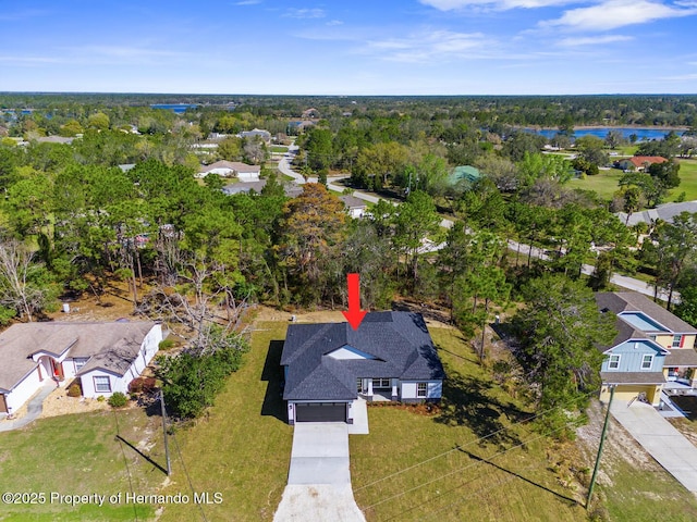 drone / aerial view featuring a wooded view, a water view, and a residential view