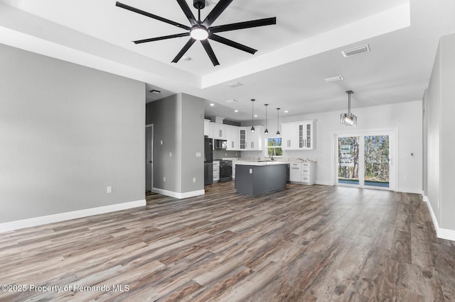 unfurnished living room featuring a sink, visible vents, baseboards, and dark wood finished floors