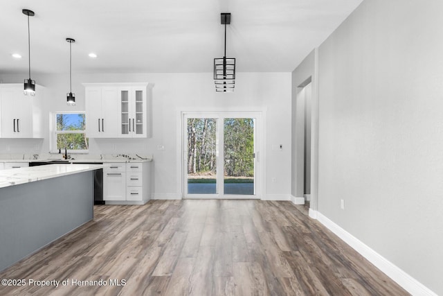 unfurnished dining area featuring recessed lighting, wood finished floors, baseboards, and a sink