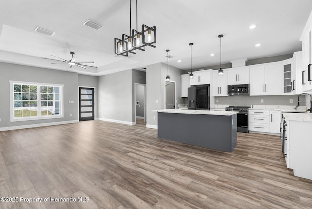 kitchen featuring visible vents, black fridge, range with gas stovetop, open floor plan, and light countertops