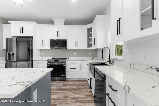 kitchen with a sink, stainless steel appliances, light wood-style floors, and white cabinetry