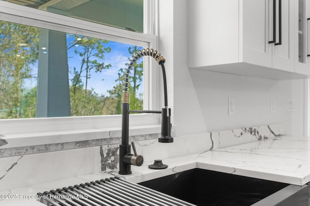 details featuring light stone countertops and white cabinets