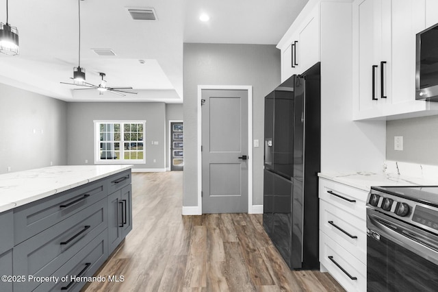 kitchen featuring visible vents, light stone countertops, appliances with stainless steel finishes, wood finished floors, and white cabinetry