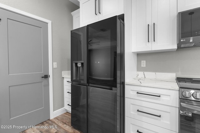 kitchen with refrigerator with ice dispenser, black electric range oven, wood finished floors, white cabinetry, and light stone countertops