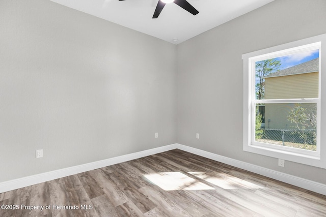 spare room with baseboards, wood finished floors, and a ceiling fan