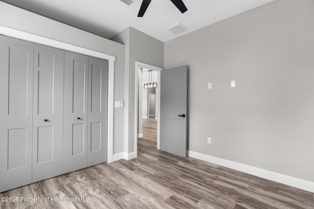 unfurnished bedroom featuring a closet, visible vents, baseboards, and wood finished floors