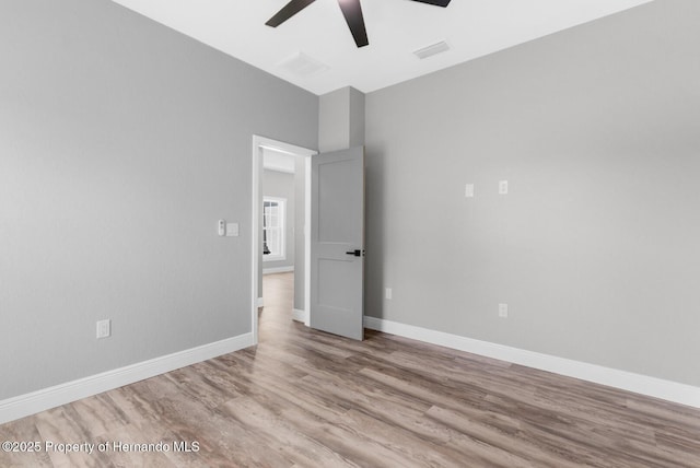 spare room featuring ceiling fan, visible vents, baseboards, and wood finished floors