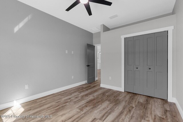 unfurnished bedroom with visible vents, baseboards, a closet, and wood finished floors