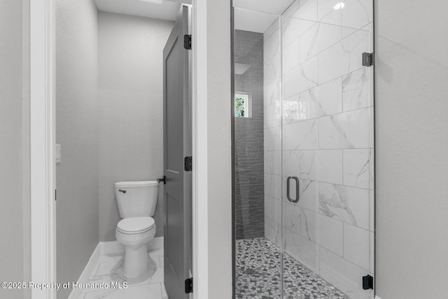 bathroom with marble finish floor, a stall shower, toilet, and baseboards