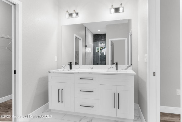 bathroom with a stall shower, baseboards, marble finish floor, and a sink