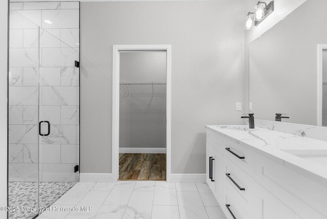 bathroom with baseboards, a stall shower, a sink, a spacious closet, and marble finish floor