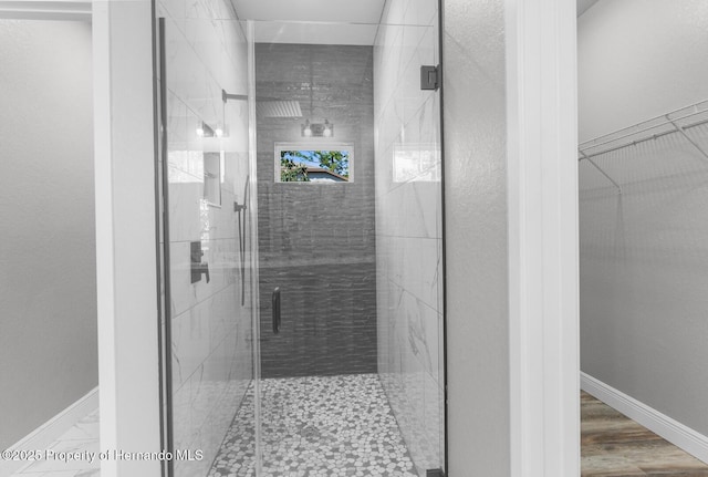 full bath featuring a walk in closet, baseboards, and a marble finish shower