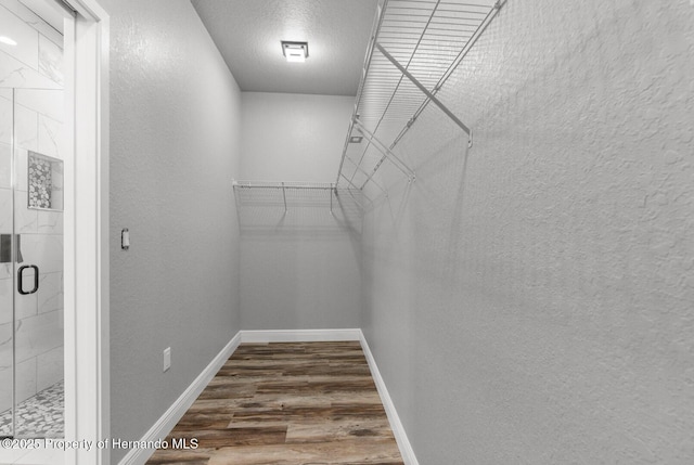 walk in closet with wood finished floors