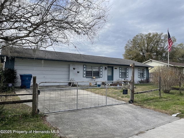 ranch-style home featuring a fenced front yard, an attached garage, concrete driveway, and a gate