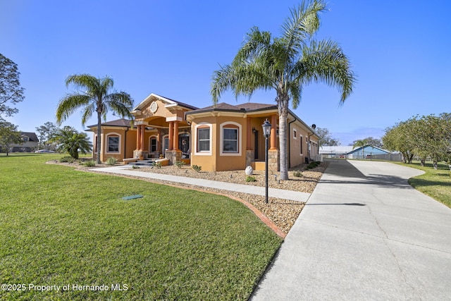 mediterranean / spanish house featuring stucco siding, a front yard, driveway, and a gate