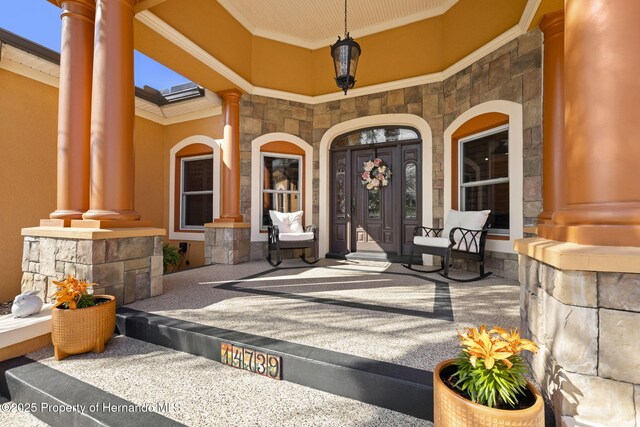 view of exterior entry with a porch and stone siding