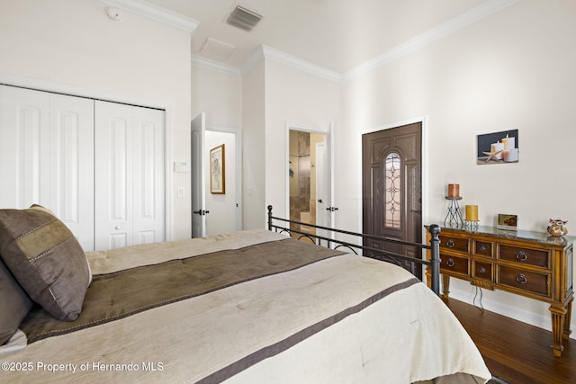 bedroom with wood finished floors, visible vents, a high ceiling, ornamental molding, and a closet