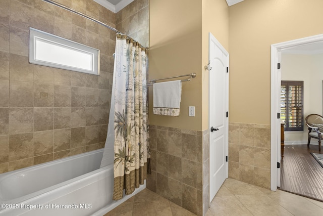 bathroom with tile patterned floors, shower / bath combination with curtain, tile walls, and wainscoting