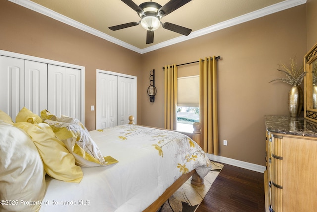 bedroom featuring a ceiling fan, baseboards, dark wood-style flooring, ornamental molding, and multiple closets