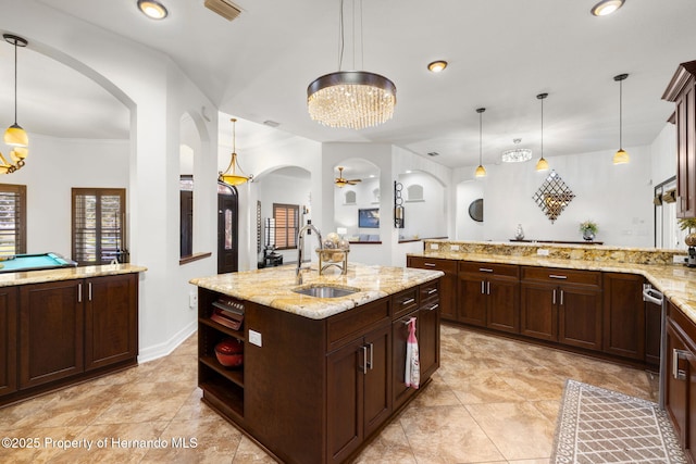 kitchen featuring visible vents, a sink, decorative light fixtures, arched walkways, and a peninsula