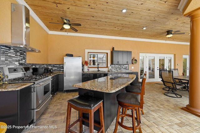 kitchen with ornate columns, stainless steel appliances, wood ceiling, crown molding, and wall chimney range hood