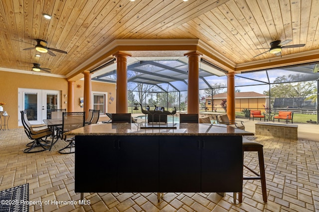 view of patio featuring glass enclosure, outdoor dining area, french doors, and outdoor dry bar
