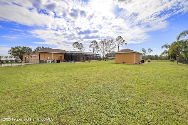 view of yard with central air condition unit, an outdoor structure, a lanai, and fence