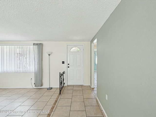 entrance foyer with light tile patterned floors, baseboards, and a textured ceiling