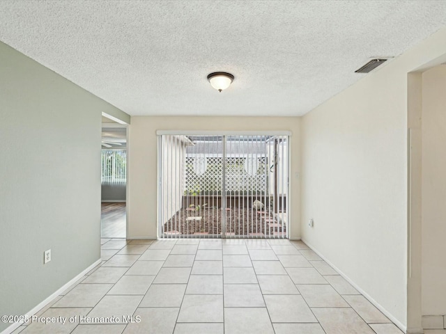 unfurnished room with light tile patterned floors, visible vents, baseboards, and a textured ceiling