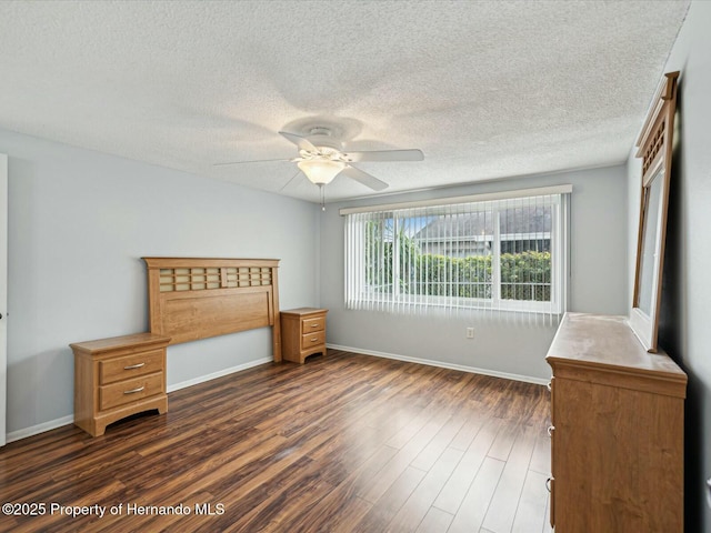 unfurnished bedroom featuring ceiling fan, dark wood-type flooring, baseboards, and a textured ceiling