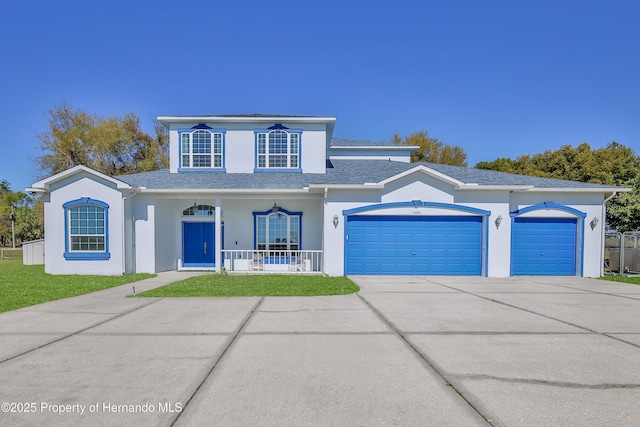 traditional-style home featuring a porch, an attached garage, driveway, and stucco siding