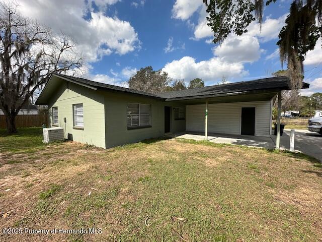 rear view of property featuring cooling unit, a patio, a lawn, and fence