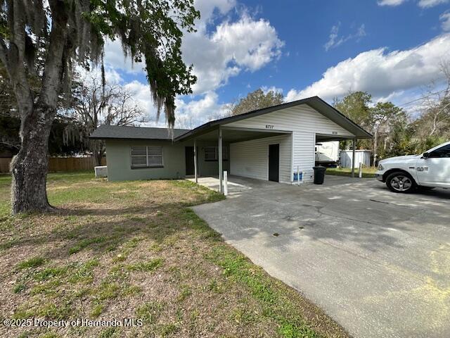 ranch-style house featuring an attached carport, concrete driveway, fence, and a front lawn