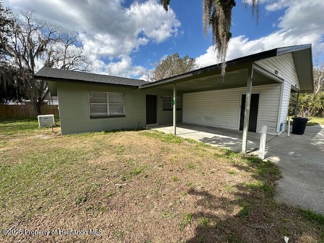 single story home with an attached carport, a front lawn, and fence