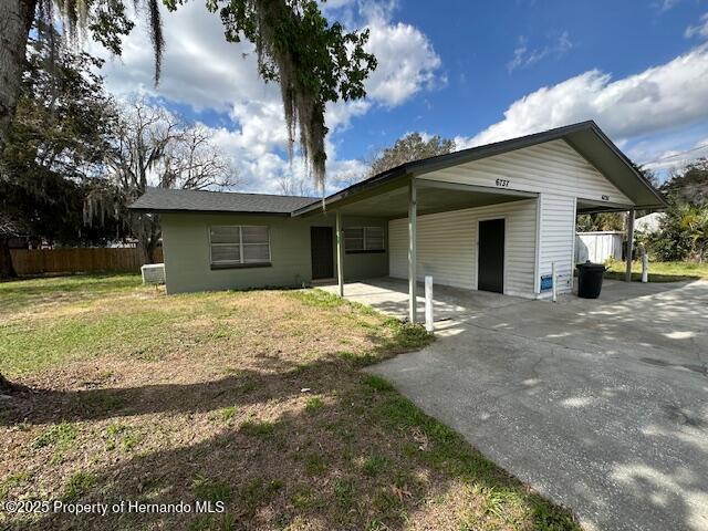 exterior space with an attached carport, concrete driveway, fence, and a front yard