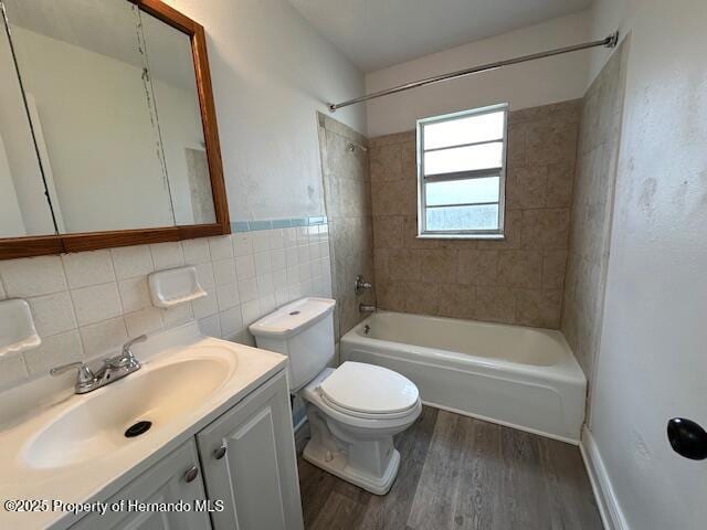 full bathroom featuring toilet, wood finished floors, tile walls, bathtub / shower combination, and vanity