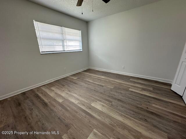 spare room featuring dark wood-style floors, baseboards, and a textured ceiling