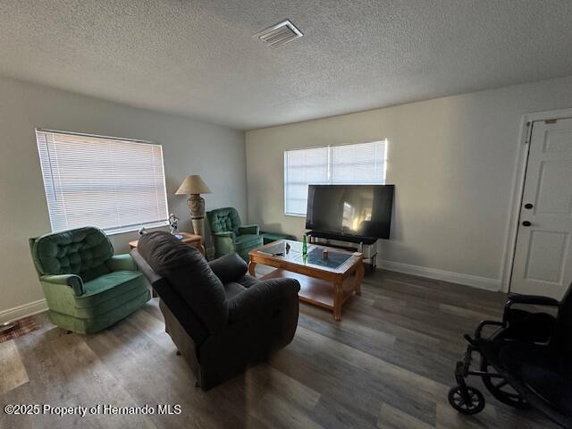 living room with visible vents, baseboards, and wood finished floors