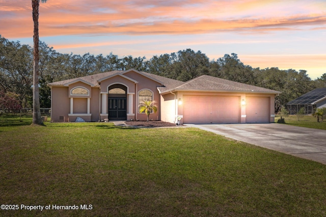 view of front facade featuring stucco siding, a lawn, driveway, fence, and an attached garage