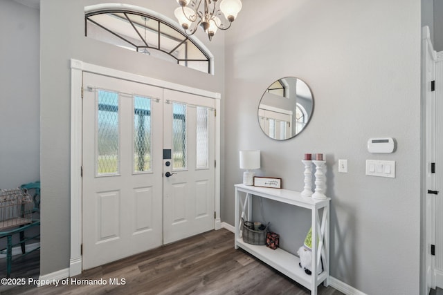 entrance foyer featuring dark wood finished floors, a notable chandelier, and baseboards