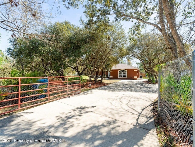 exterior space featuring concrete driveway, a gate, and fence