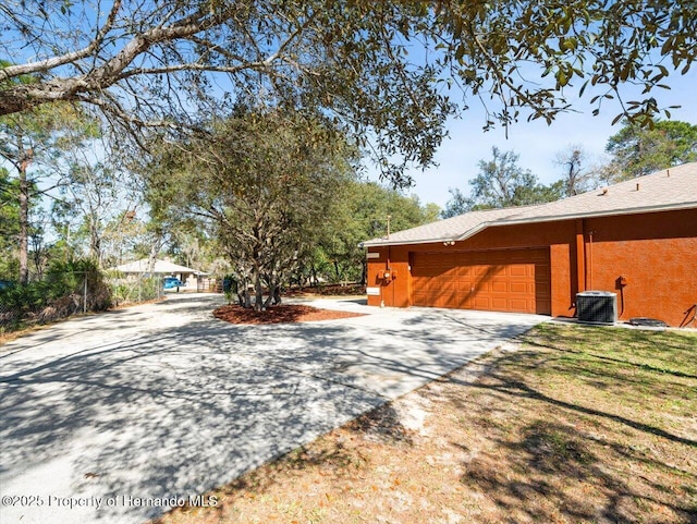 view of home's exterior featuring central air condition unit, a lawn, and concrete driveway