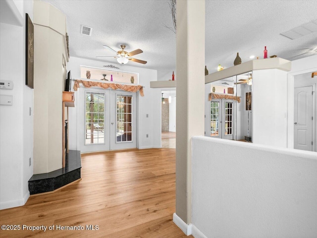 foyer with visible vents, ceiling fan, french doors, wood finished floors, and a textured ceiling