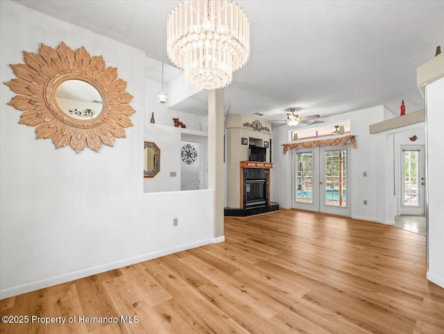 unfurnished living room with a glass covered fireplace, baseboards, a textured ceiling, and wood finished floors