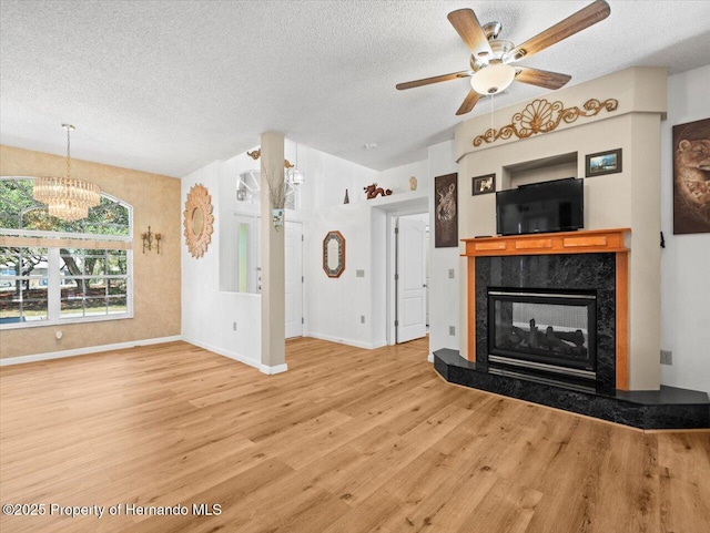 unfurnished living room featuring a fireplace, a textured ceiling, baseboards, and wood finished floors