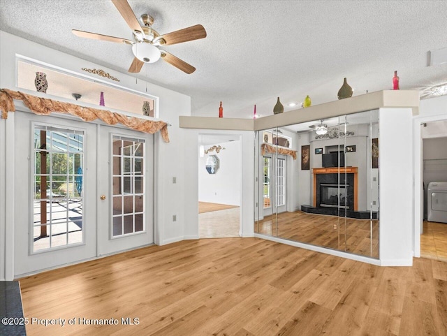 unfurnished living room featuring washer / dryer, a fireplace, french doors, and wood finished floors